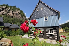 A traditional wooden house with a steep roof, a small window, and a stone pathway leading to it. - Oberlausitzer Feha Mountain Cottage (Kurort Oybin)