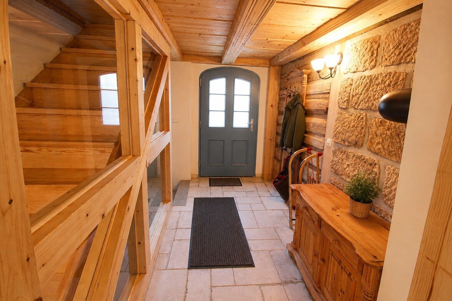 Un interior de madera con una escalera, una puerta y una pared de piedra.
