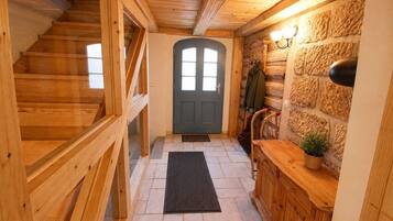 Un interior de madera con una escalera, una puerta y una pared de piedra.