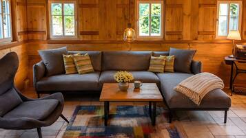 A cozy log cabin interior with a sectional sofa, a coffee table, and a fireplace.