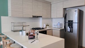 Una cocina moderna con un refrigerador de acero inoxidable, un microondas y una estufa a gas.
