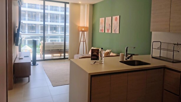 Una cocina moderna con una isla grande, un comedor con vistas y una pared de acento verde.