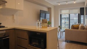 A modern kitchen with a built-in microwave, a small dining area, and a sofa in the living room. - w Cozy 2BR w Balcony in Miraflores (Lima)