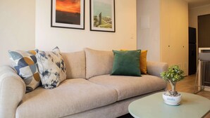 A living room with a sofa, two framed pictures, and a small table with a plant. - w Cozy 2BR w Balcony in Miraflores (Lima)