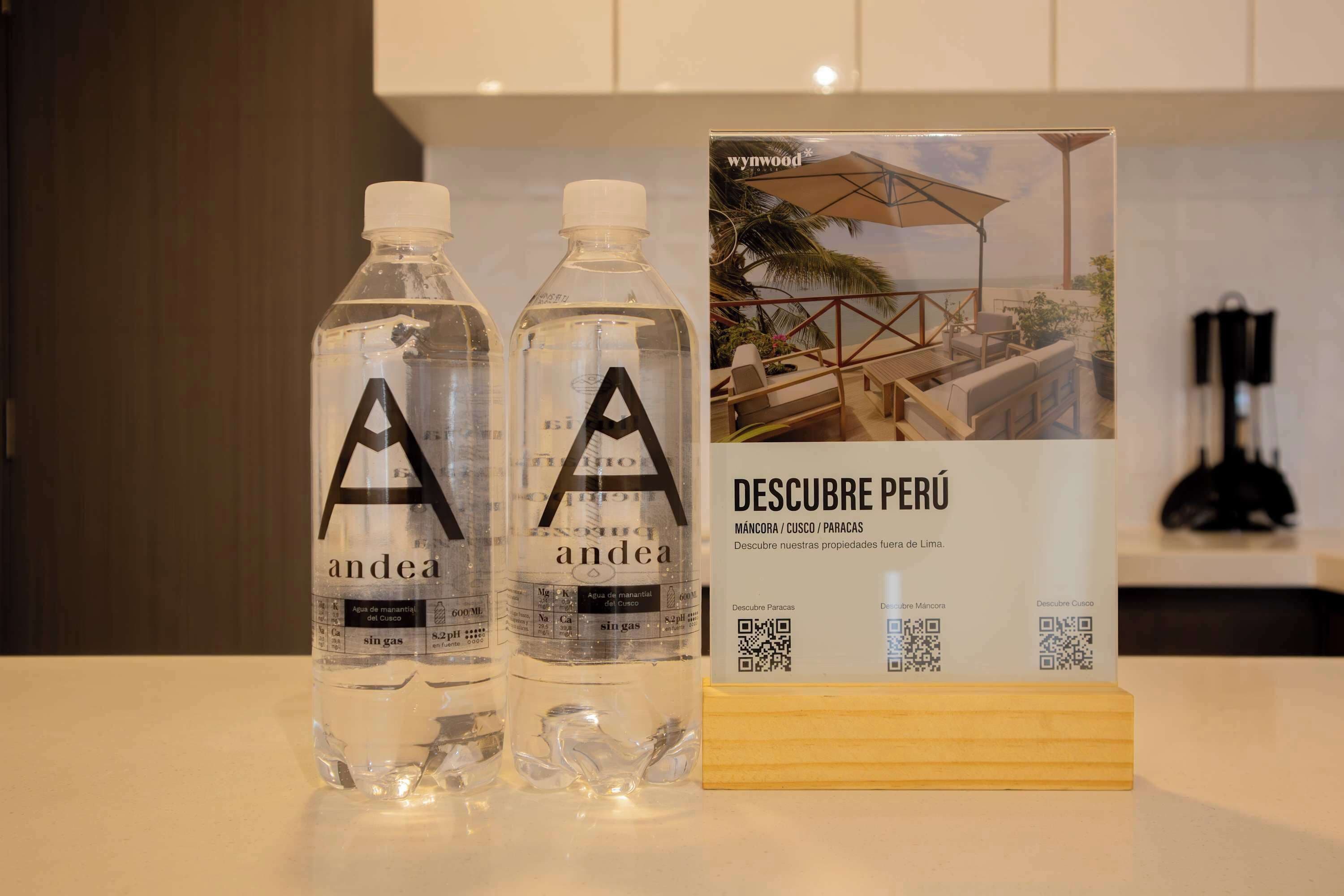 Dos botellas de agua con la etiqueta 'andea' y un folleto titulado 'DESCUBRE PERÚ' con códigos QR.