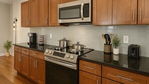 Una cucina moderna con mobili in legno, un fornello in acciaio inossidabile, un forno a microonde e un tostapane.