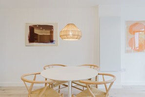A dining area with a round table and four chairs, a hanging light fixture, and two framed artworks on the wall. - Beautifully Curated 2BD Flat, Heart of East London (Greater London)
