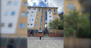 A multi-story residential building with a central entrance, a gated driveway, and a small tree in the foreground. - Beautifully Curated 2BD Flat, Heart of East London (Greater London)