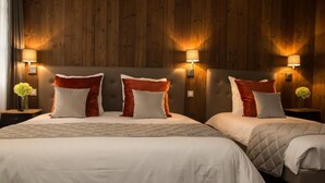 A hotel room with two beds, wooden panel walls, and wall-mounted lamps. - Les Chambres de Louise (Habsheim)