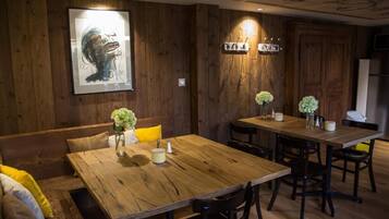 Un comedor de madera con una mesa grande y bancos, una obra de arte enmarcada en la pared y una lámpara moderna.