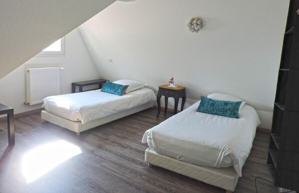 A bedroom with two beds, a small table, and a radiator.