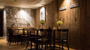 A dining area with a wooden wall, a bench, and a table with chairs. - Les Chambres de Louise (Habsheim)