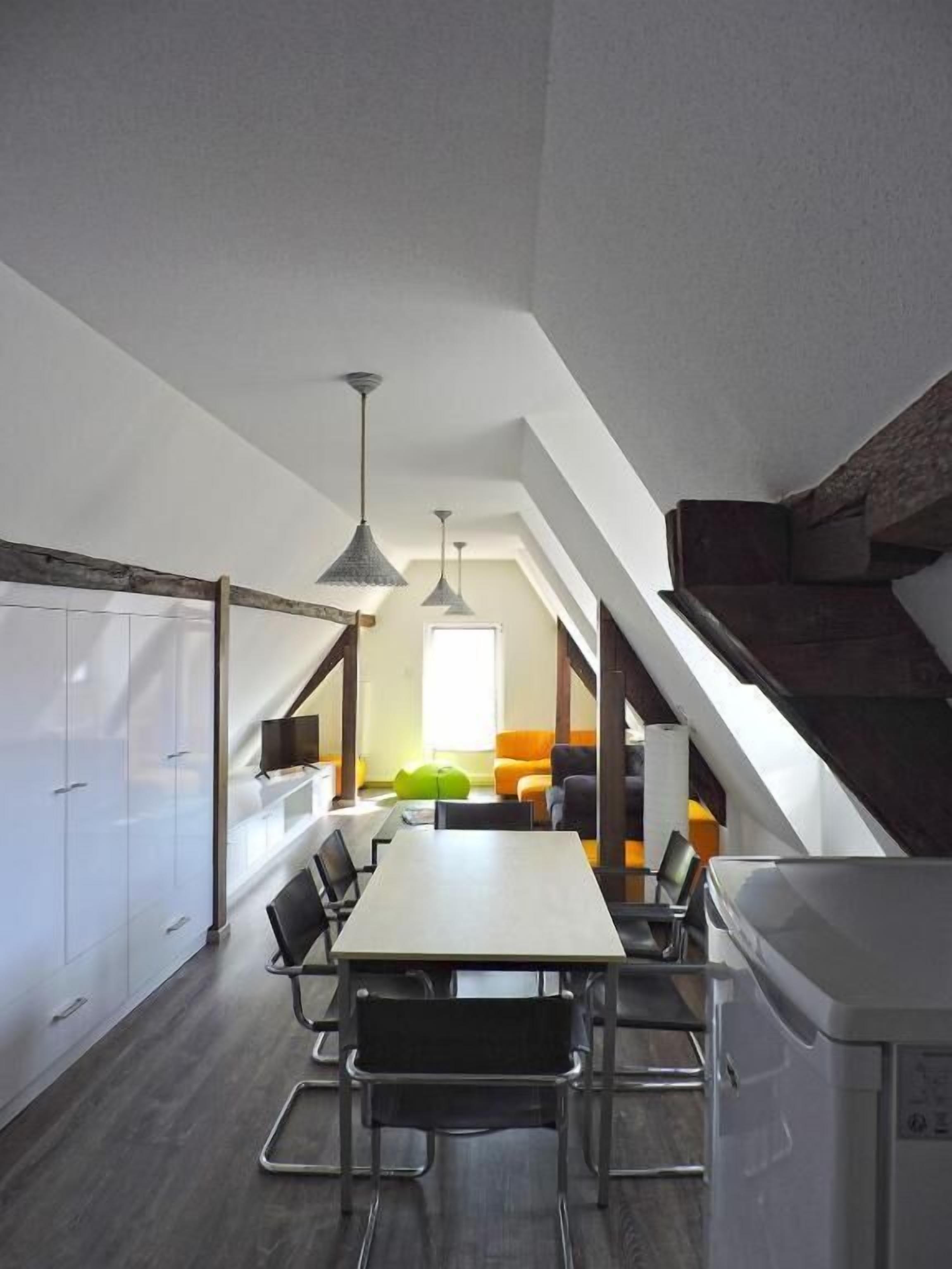 Una cocina moderna con una larga mesa de comedor, armarios empotrados e iluminación colgante.