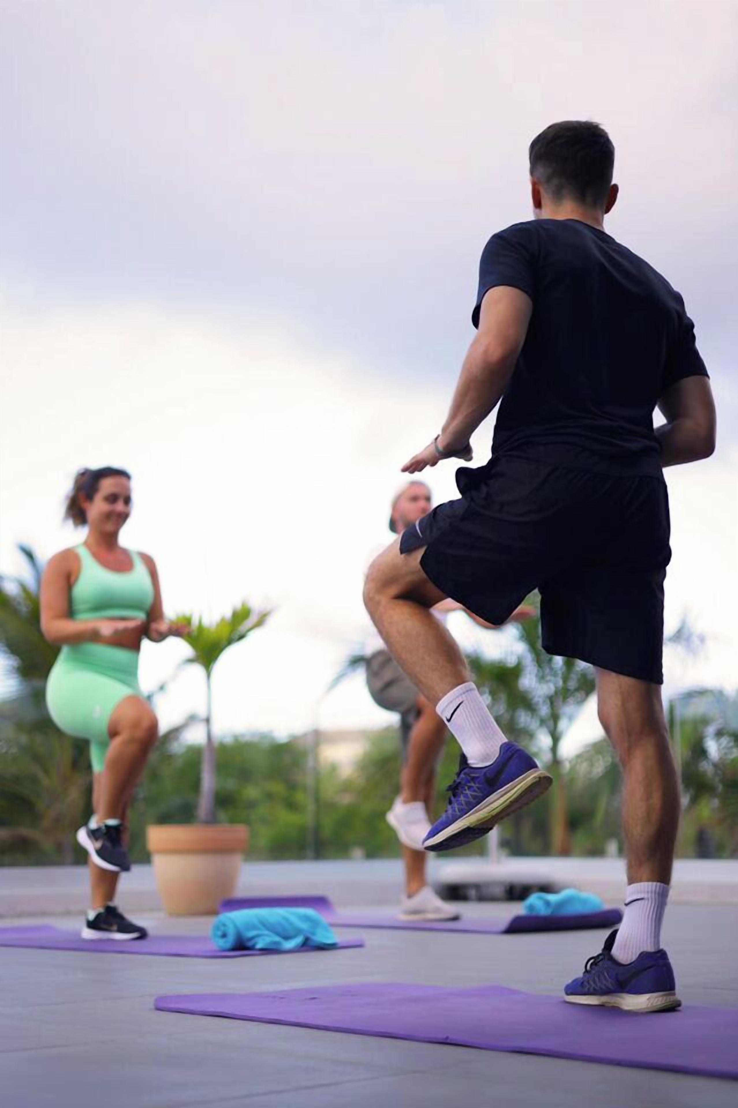 Three people exercising on outdoor mats.