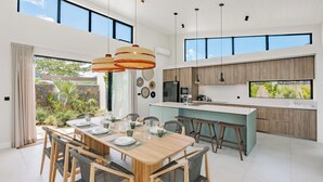 A modern kitchen with wooden cabinets, a central island, and pendant lighting. - Eko Savannah by MJ Holidays (Tamarin)
