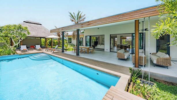 A modern outdoor pool area with lounge chairs and a thatched-roof structure. - Eko Savannah by MJ Holidays (Tamarin)