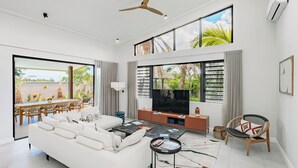 A spacious living room with a large sofa, a TV, and a dining area with a table and chairs. - Eko Savannah by MJ Holidays (Tamarin)