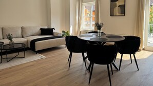 Un salon moderne avec un canapé, une table à manger ronde entourée de chaises, une table basse et une plante en pot.