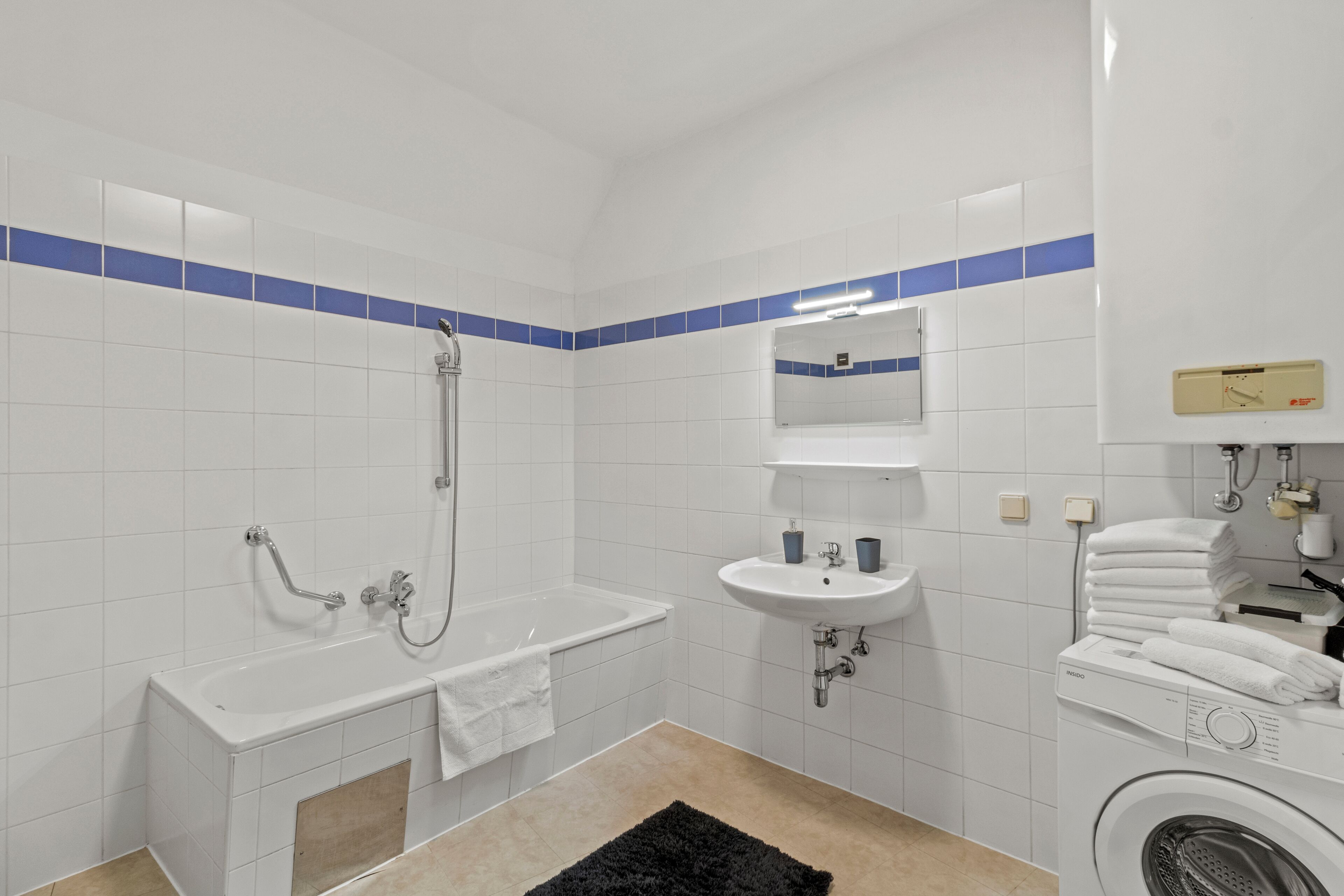 Ein Badezimmer mit Badewanne, Waschbecken, Spiegel und Waschmaschine.
