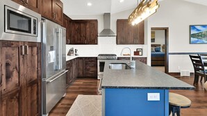 A modern kitchen with wooden cabinets, stainless steel appliances, and a blue island.