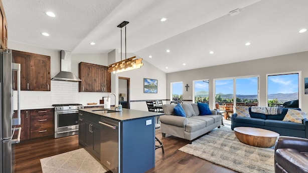 A modern kitchen with wooden cabinets, a central island, and a dining area with a sofa and coffee table.