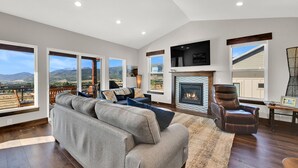 A spacious living room with a large gray sectional sofa, a fireplace, and a mounted TV.