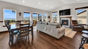 A spacious living room with a fireplace, large windows, and a dining area.