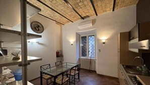 Cocina compacta con comedor, un reloj en la pared y una ventana con vistas.