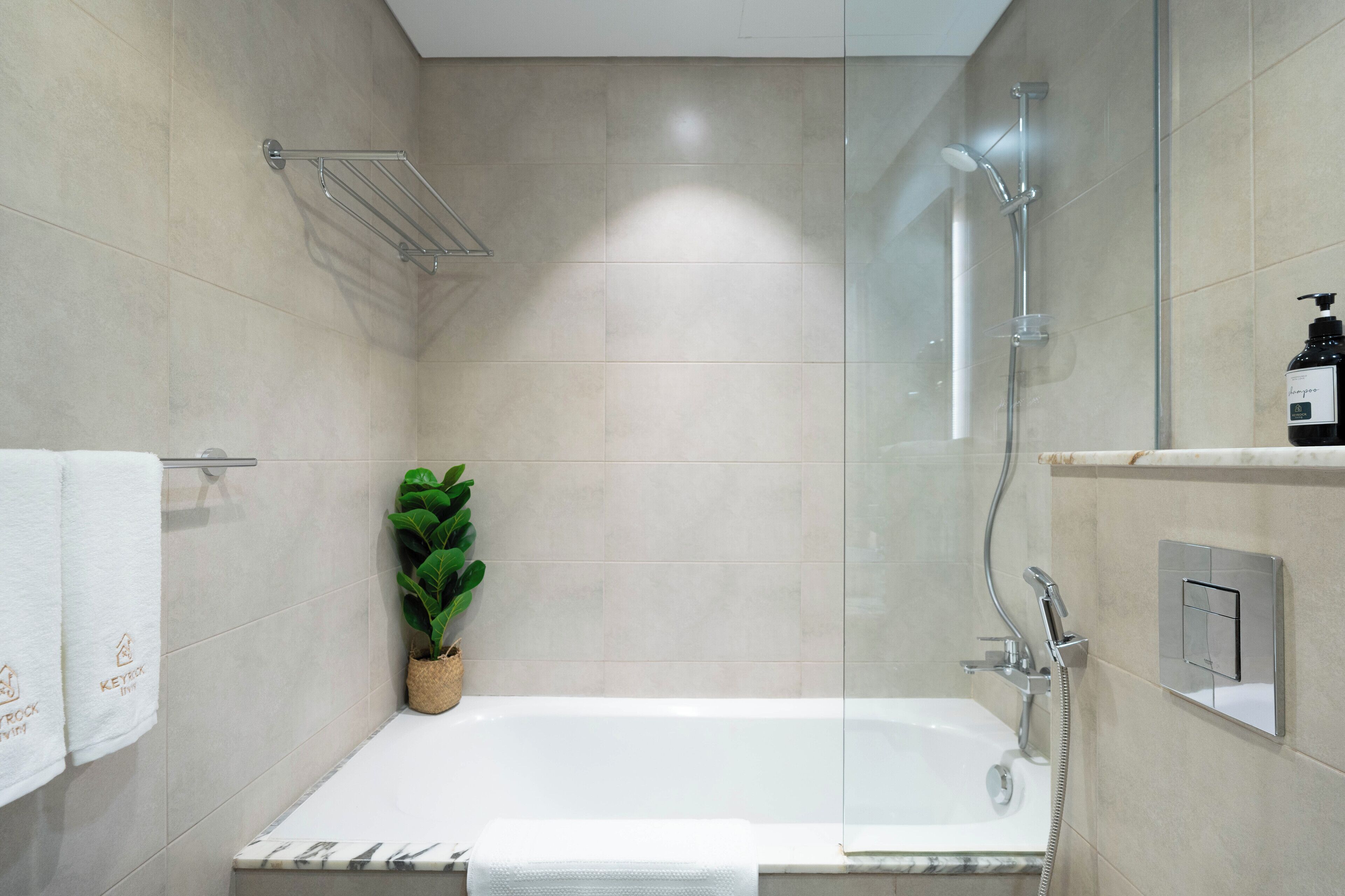 A modern bathroom with a bathtub, shower, and a potted plant.