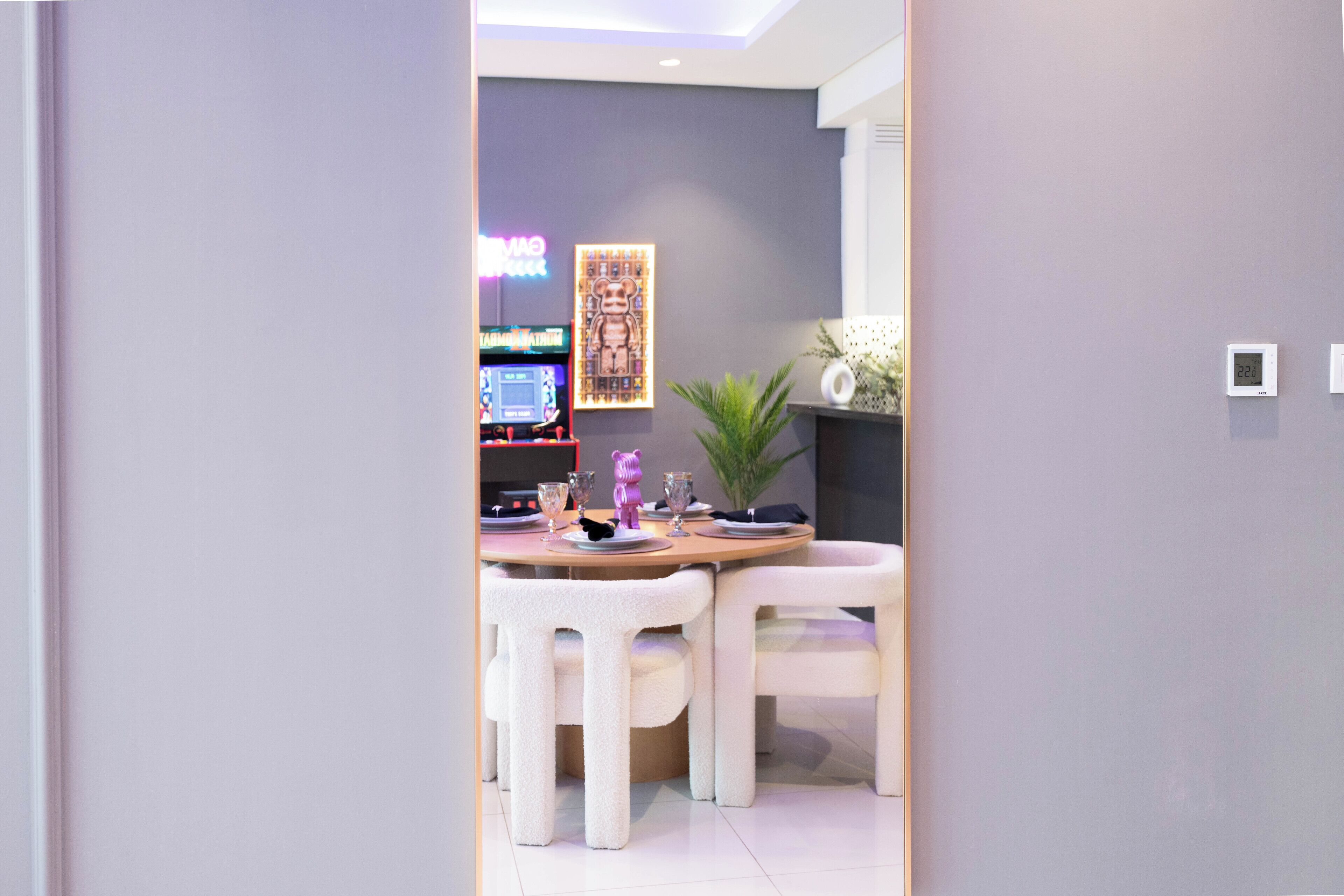 A modern dining area with a round table, white chairs, and a decorative plant.