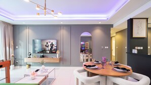A modern living room with a dining area, a TV, and a mirror. - Exclusive Paramount 2BR - Skyline (Dubai)