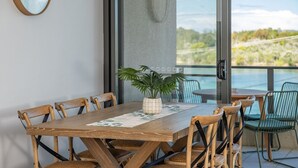 A wooden dining table with chairs, a potted plant, and a view of a natural landscape through large windows. - Lago Vista on the Forster lakefront (Forster)
