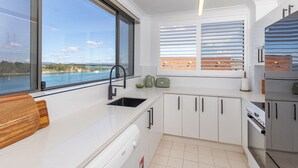 A modern kitchen with a large window, a built-in sink, and a view of a body of water. - Lago Vista on the Forster lakefront (Forster)