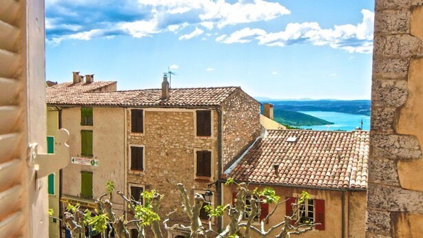 Un bâtiment en pierre avec un toit en tuiles, une cheminée bien visible et une vue sur la mer.