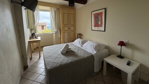 Une chambre à coucher avec un lit, une table de chevet, une lampe et une fenêtre avec des rideaux.