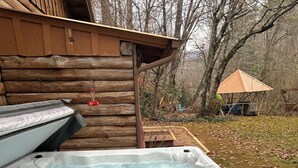 A hot tub with a wooden deck and a wooden cabin in the background. - Moonlight Creekside Honeymoon Adult Only Cabin accepts small pups up to 20 lbs (Sautee Nacoochee)