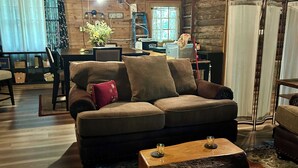 A cozy living room with a wooden ceiling, a sofa, a coffee table, and a patterned rug. - Moonlight Creekside Honeymoon Adult Only Cabin accepts small pups up to 20 lbs (Sautee Nacoochee)