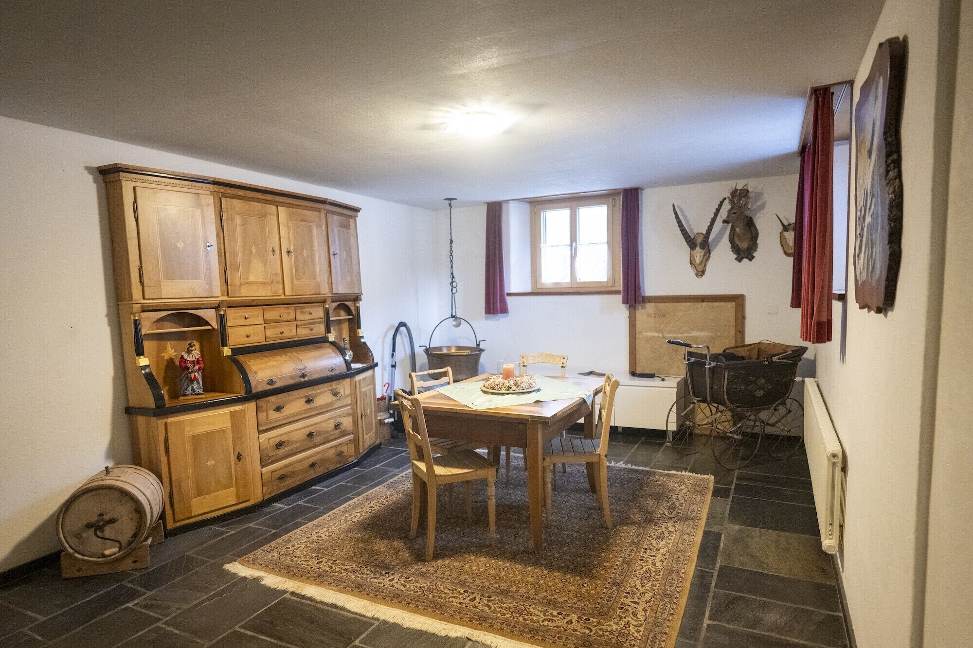 Un coin repas comprenant une table et des chaises en bois, un tapis, un meuble en bois et un radiateur.