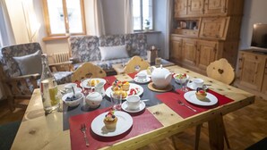 A dining table set with plates, cups, a teapot, and a bottle. - Chasa Bügliet: Holiday flat in the village center of Sent (Sent)