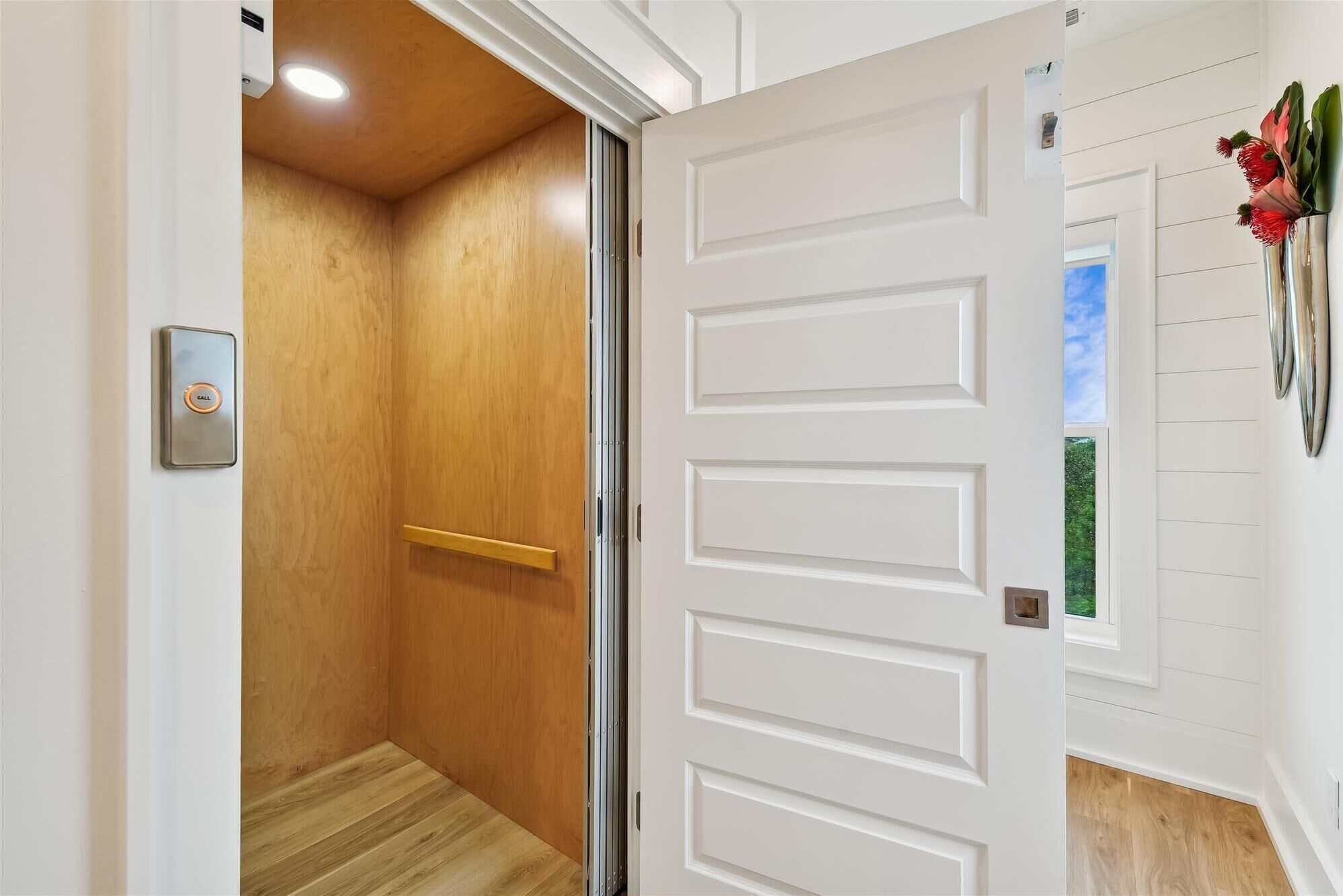 Un couloir avec une porte en bois et une porte blanche dotée d’une poignée.