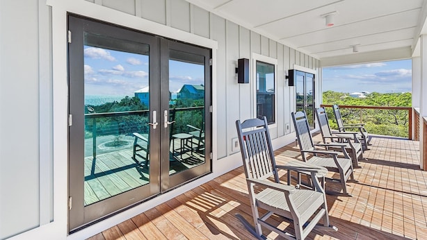 A covered outdoor area with sliding glass doors, wooden deck, and outdoor seating.