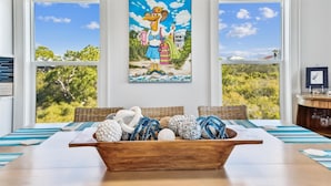 A dining area with a wooden table, wicker chairs, and a bowl of decorative items.