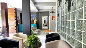 A modern lobby with a world map mural, comfortable seating, a coffee table, and a staircase. - Foresthouse Beach Hostel (Florianópolis)