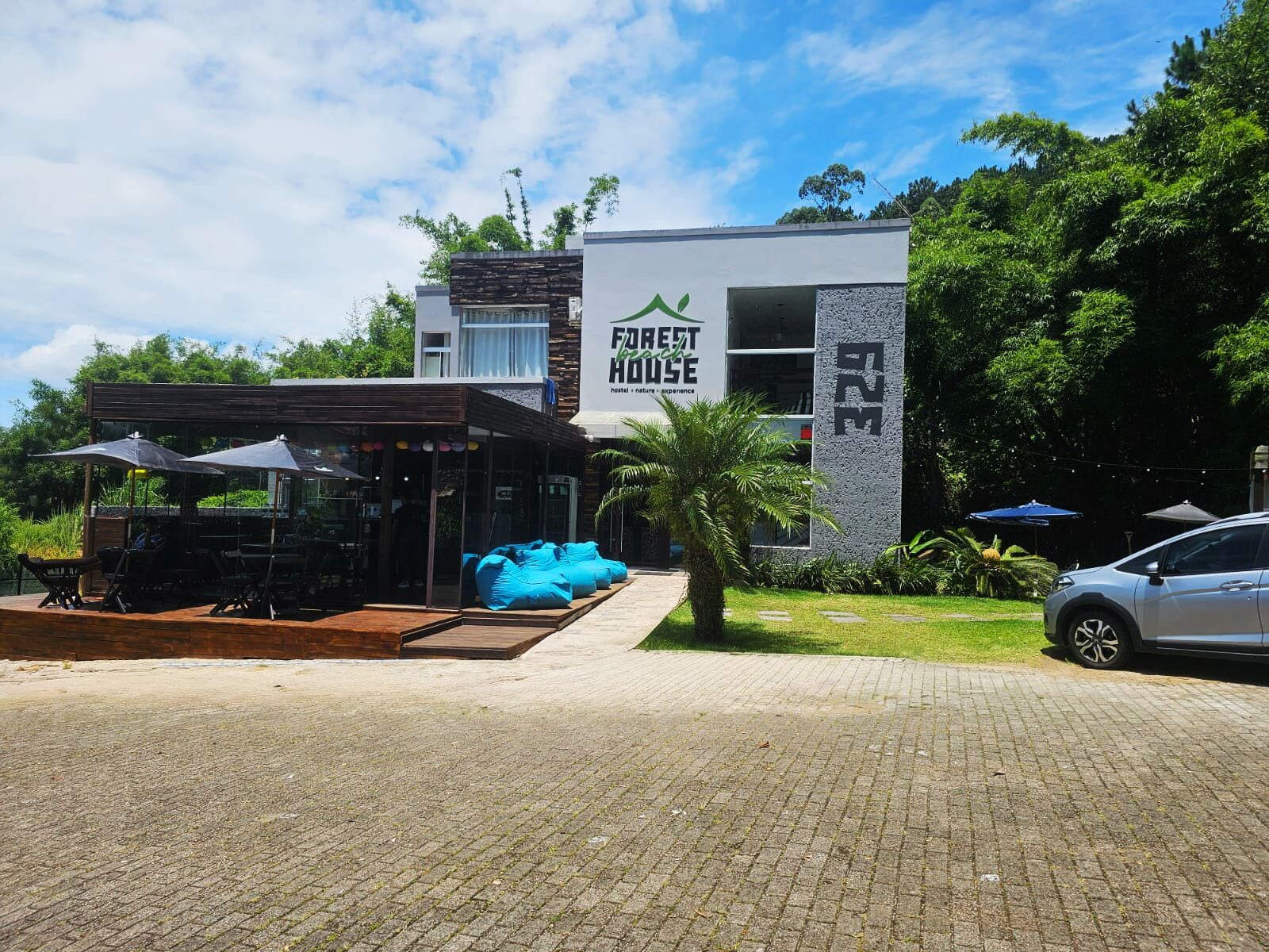 A modern building with a sign reading "FOREST HOUSE" and a car parked in front.