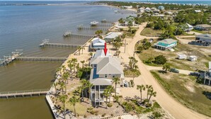 An aerial view of a coastal property with a large house, a dock, and a beach.