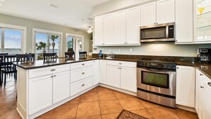 A modern kitchen with white cabinets, a stainless steel oven, and a microwave.