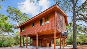 Une maison en bois à deux étages, dotée d’un porche couvert et d’un escalier menant à l’étage supérieur.