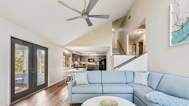 Un salon spacieux avec un canapé d’angle bleu clair, une table basse blanche et un ventilateur de plafond.
