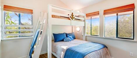 Habitación con literas, una escalera, dos ventanas con persianas y vista a árboles.