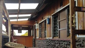 Un espacio al aire libre cubierto con un muro de piedra, una puerta de madera y una silla de mimbre.